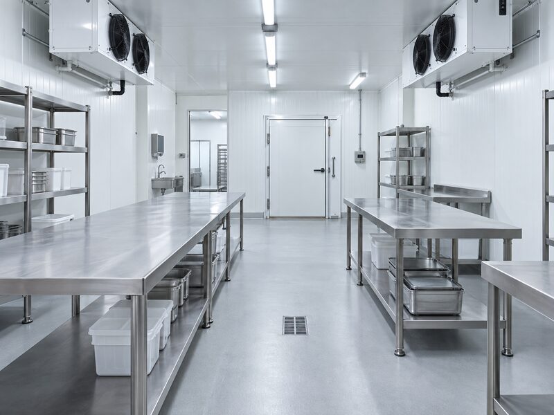 Temperature-controlled food room with stainless tables and insulated walls.